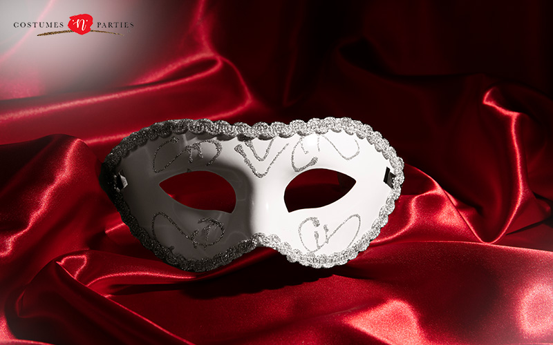 White masquerade mask with silver glitter on red satin fabric, emphasizing elegance and theatrical flair.